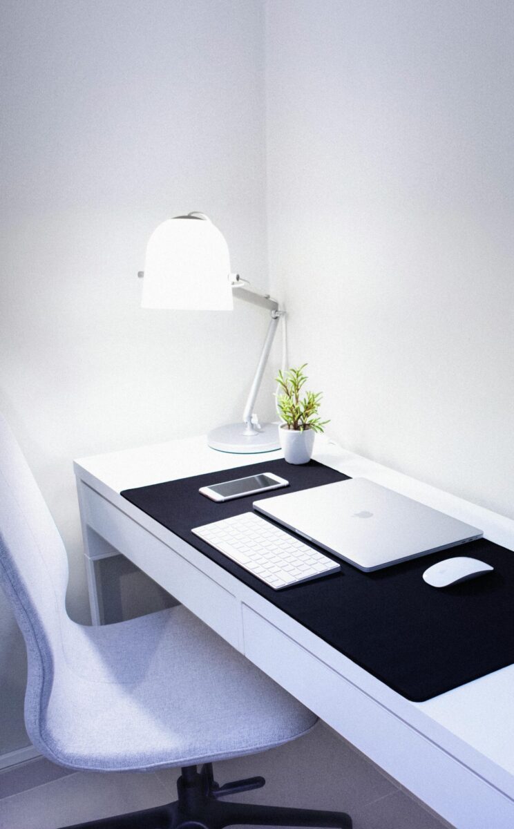 Sleek, modern home office setup featuring Apple devices, a desk lamp, and a plant.